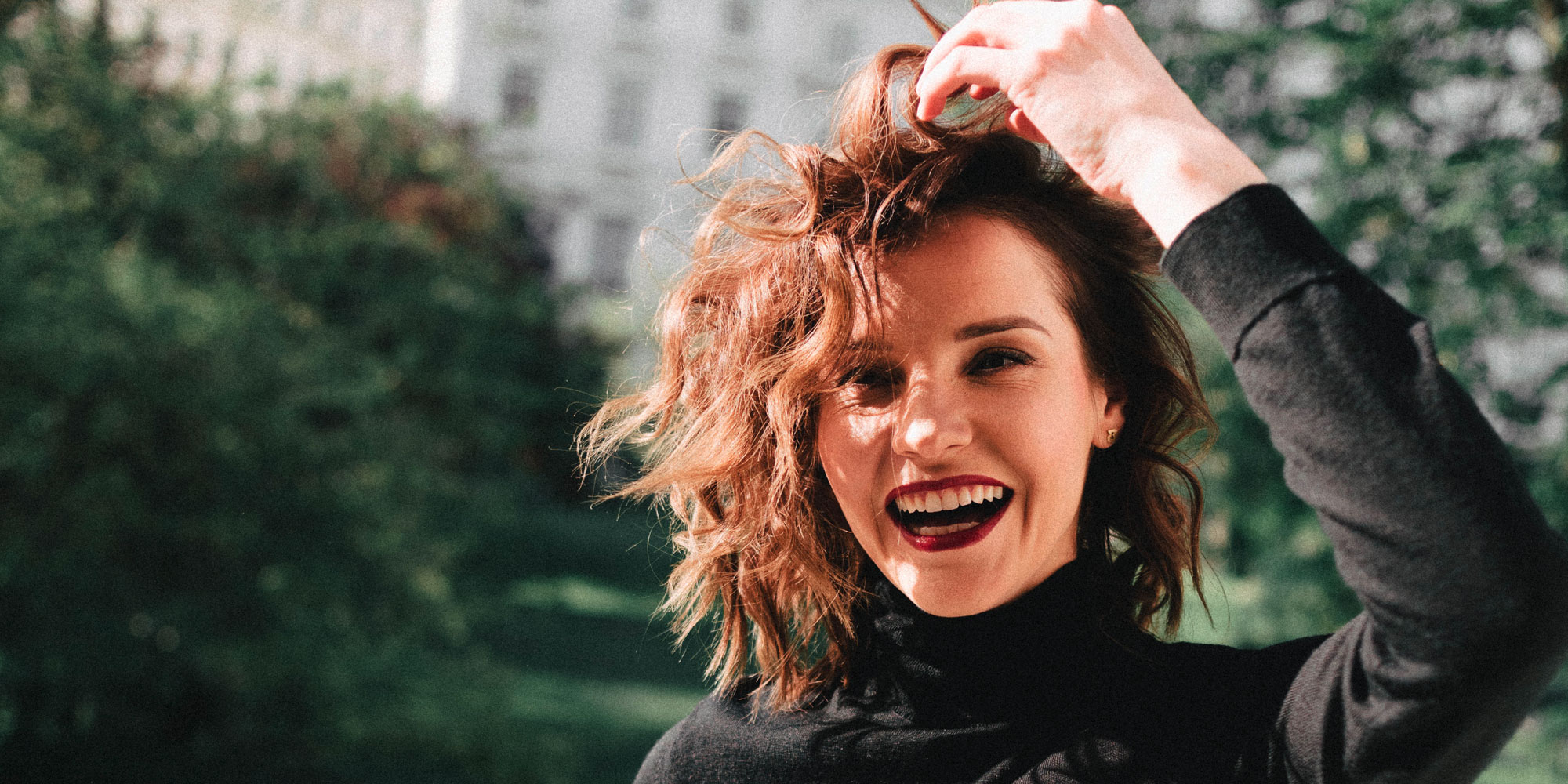 woman with a big smile sitting outside in the sun at a park